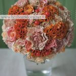 Свадебный букет из персиковых и розовых роз и гвоздик с оранжевыми ягодами и целозией