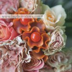 Свадебный букет из персиковых и розовых роз и гвоздик с оранжевыми ягодами и целозией