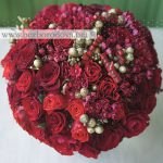 Красный букет из роз с кораллами и золотой брунией