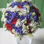 Синий свадебный букет с красными розами, белым восковником и ягодами