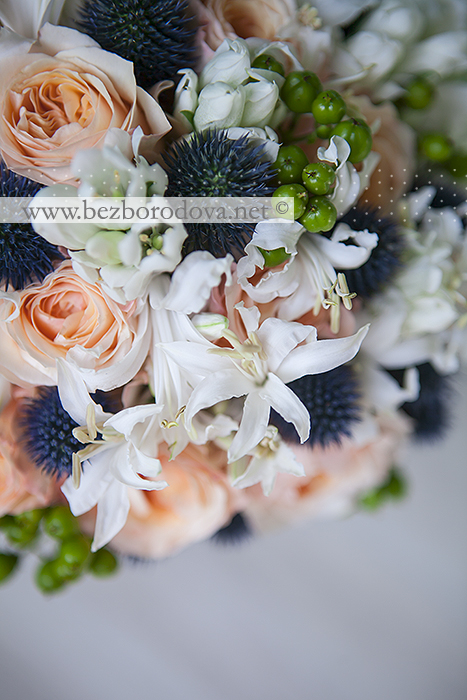 Нежный свадебный букет из персиковых пионовидных роз с зелеными ягодами и синим эрингиумом
