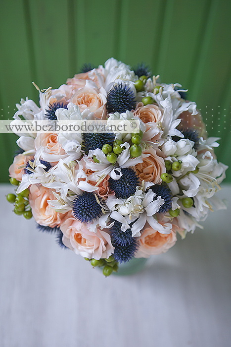 Нежный свадебный букет из персиковых пионовидных роз с зелеными ягодами и синим эрингиумом