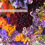 Свадебный букет с георгинами винного цвета, оранжевыми розами, сиреневой гвоздикой и статицей