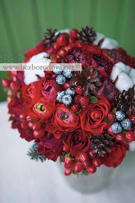 Зимний свадебный букет из красных ранункулюсов, роз, ягод  с хлопком и шишками