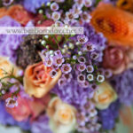 Яркий летний букет невесты из оранжевых и персиковых роз с сиреневой гвоздикой