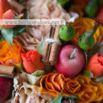 Яркий осенний букет из красных роз с яблоками, зелеными ягодами и хризантемой