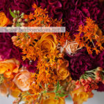 Осенний букет в подарок из оранжевых роз, асклепии, винных гвоздик и целозии