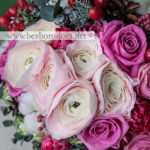 Зимний букет невесты из кремовых ранункулюсов с шишками, красными ягодами, розовыми розами, тюльпанами и эвкалиптом