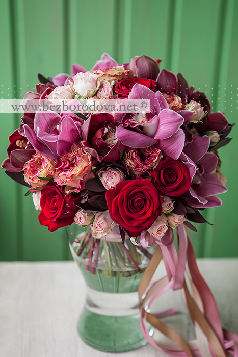 Букет цвета марсала из орхидей цимбидиум, розовых пионовидных роз, красных роз и винного леукадендрона 